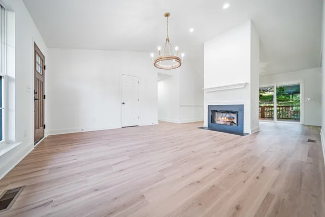 an empty room with wooden floor fireplace and windows