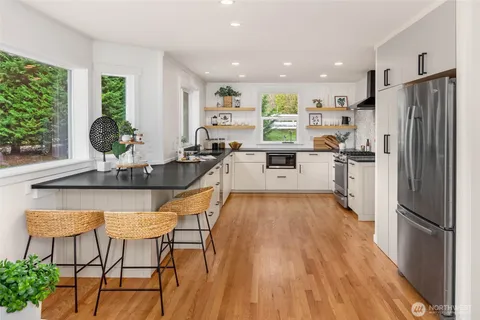 a kitchen with stainless steel appliances a refrigerator a stove a sink dishwasher with a dining table and chairs with wooden floor