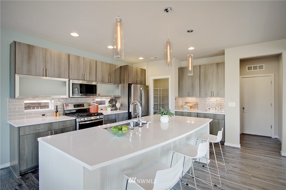 4322 232nd Place Southeast, Unit 5 Bothell, WA 98021 - Photo 6 of 31 a kitchen with stainless steel appliances granite countertop a sink a stove a refrigerator a microwave oven with white cabinets and wooden floor