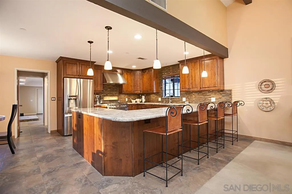 16987 Lyons Valley Road Jamul, CA 91935 - Photo 7 of 25 a kitchen with stainless steel appliances kitchen island granite countertop a table chairs and a refrigerator