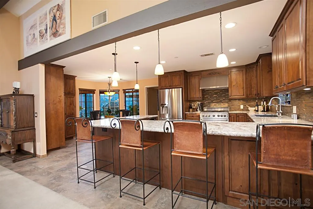 16987 Lyons Valley Road Jamul, CA 91935 - Photo 8 of 25 a kitchen with stainless steel appliances kitchen island granite countertop a table chairs and a refrigerator