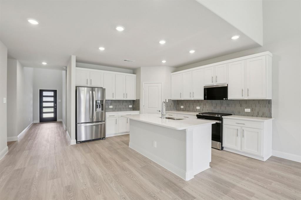 2206 Windy Trail Princeton, TX 75407 - Photo 3 of 34 a kitchen with stainless steel appliances kitchen island sink refrigerator and microwave