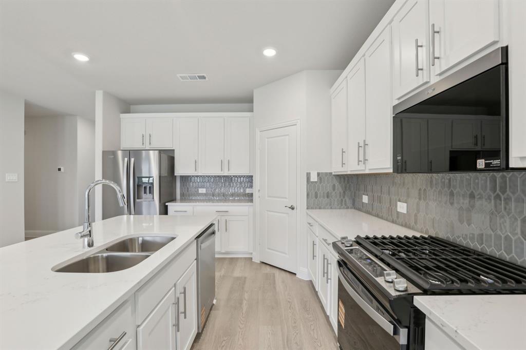 2206 Windy Trail Princeton, TX 75407 - Photo 4 of 34 a kitchen with stainless steel appliances a sink a stove and cabinets