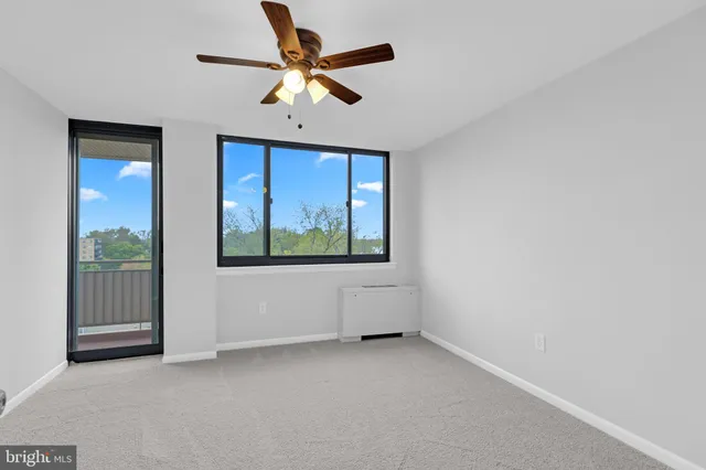 an empty room with windows and fan