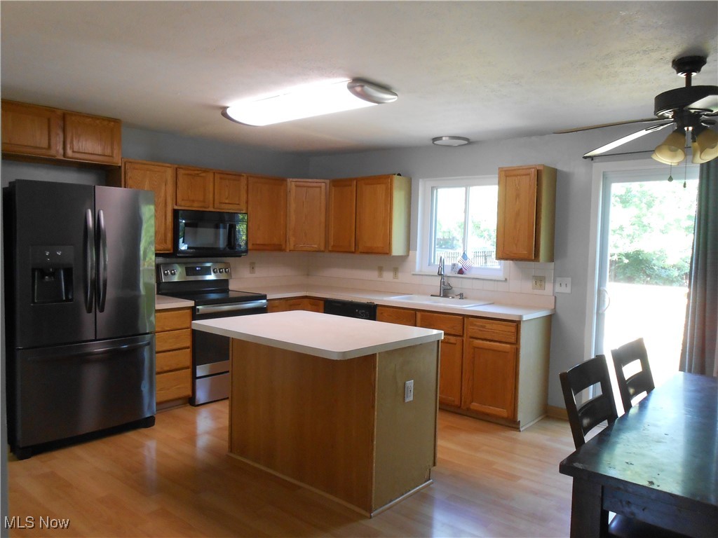 17022 Howe Road Strongsville, OH 44136 - Photo 6 of 22 Kitchen featuring black appliances, light wood-style floors, light countertops, ceiling fan, and a kitchen island