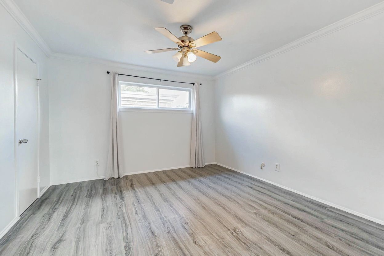6402 Del Monte Drive, Unit 65 Houston, TX 77057 - Photo 15 of 21 an empty room with wooden floor chandelier fan and windows