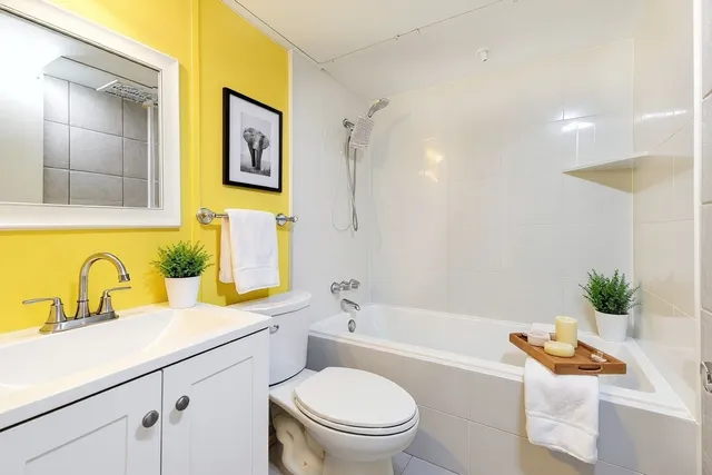 a bathroom with a granite countertop sink mirror vanity bathtub and a toilet