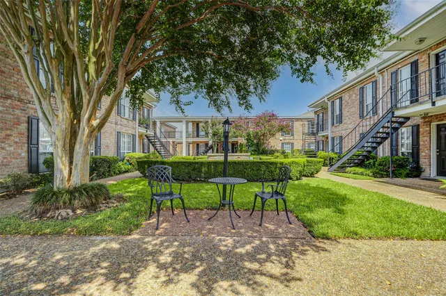 a view of a house with a yard and table and chairs under large tree