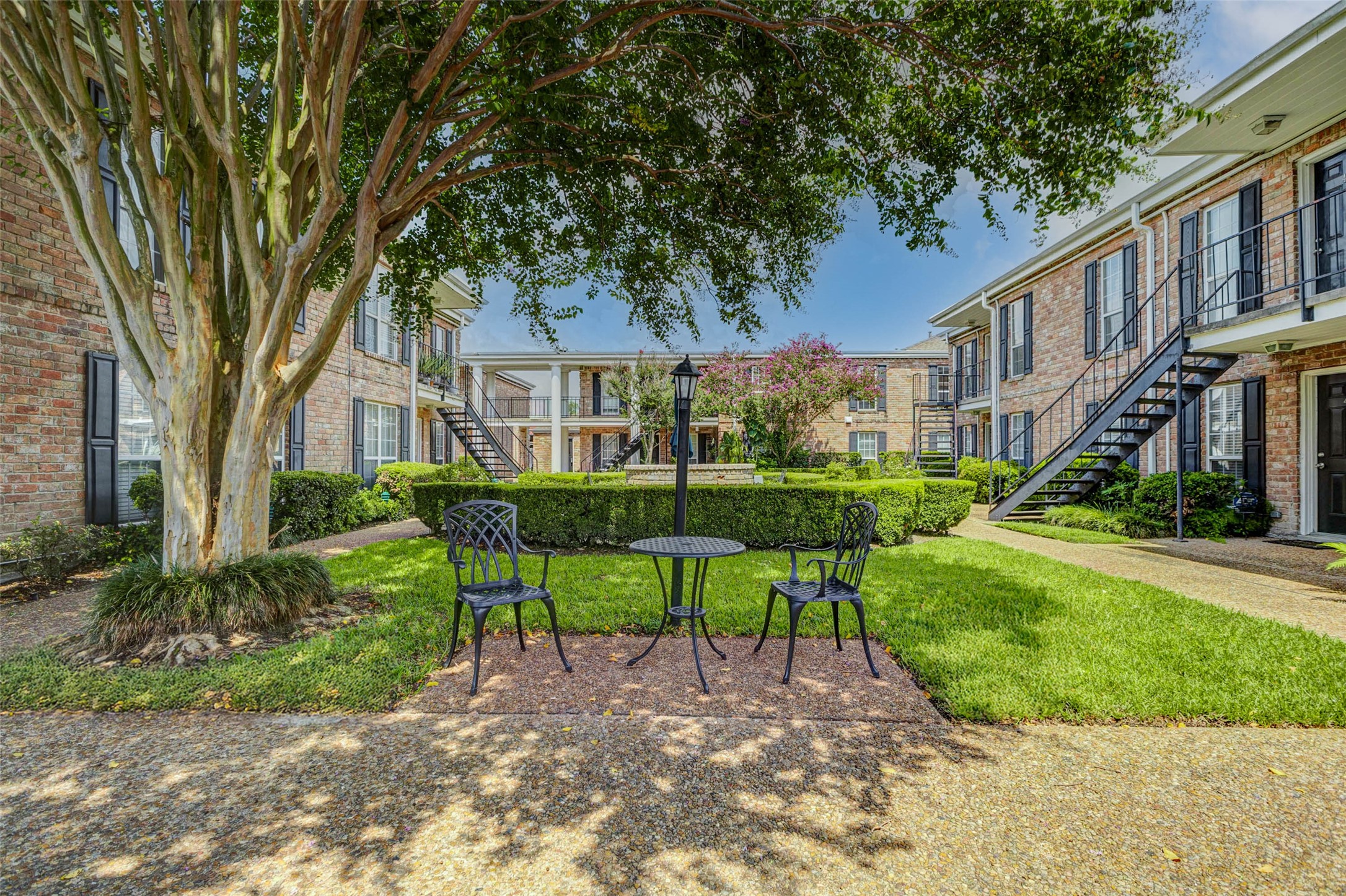 6402 Del Monte Drive, Unit 65 Houston, TX 77057 - Photo 20 of 21 a view of a house with a yard and table and chairs under large tree