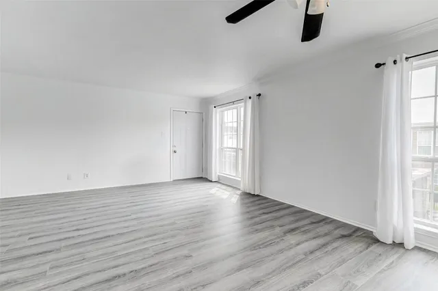 an empty room with wooden floor cabinet and windows