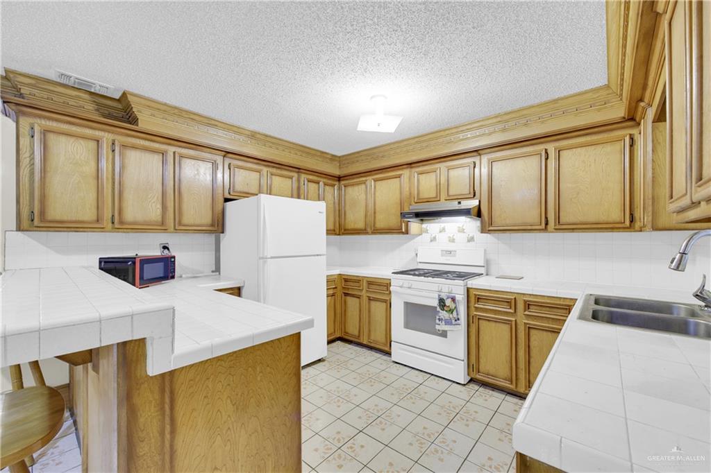 18 Bellas Lane Rio Grande City, TX 78582 - Photo 6 of 28 a kitchen with stainless steel appliances granite countertop a refrigerator sink stove and white cabinets