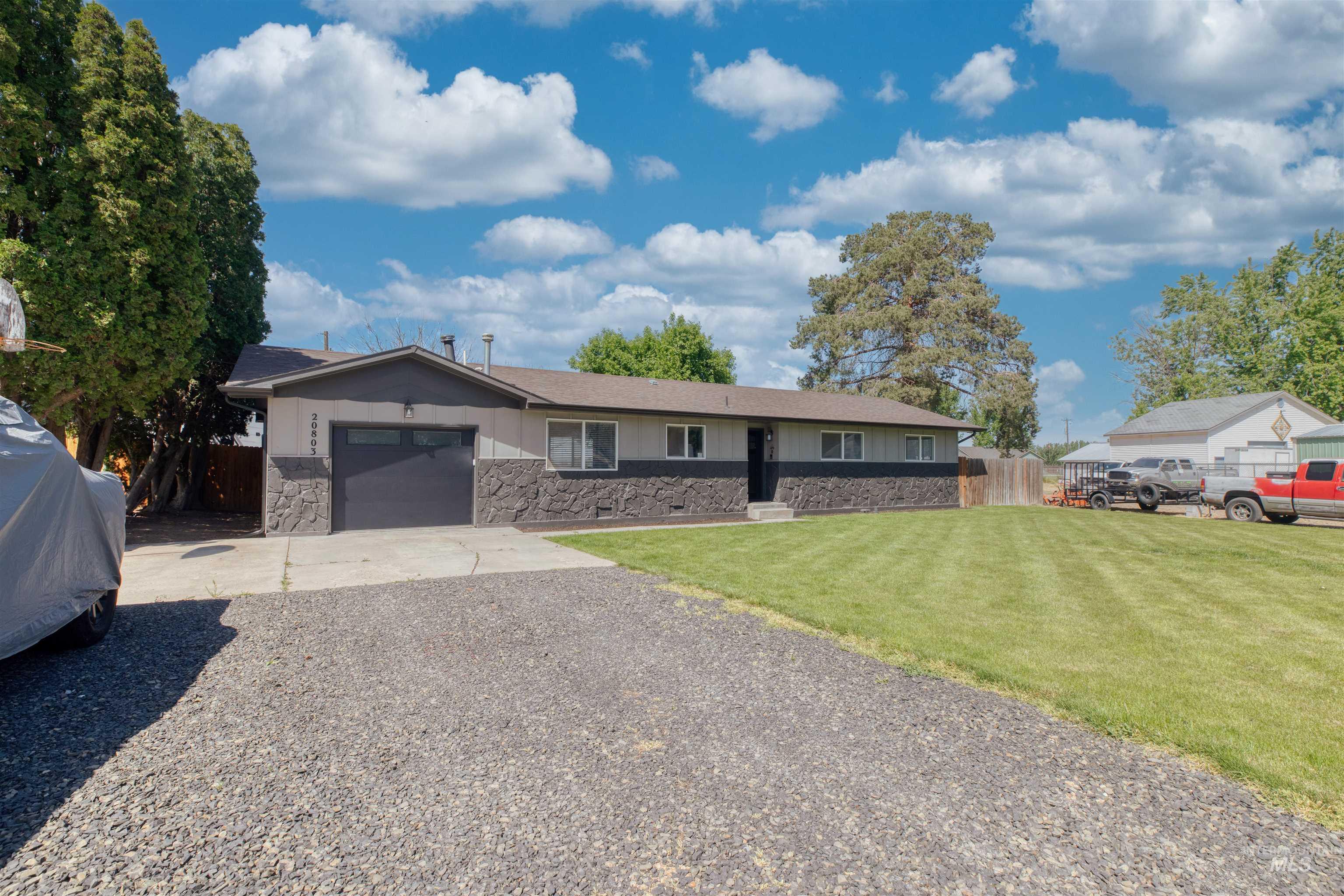 20803 Friends Road Greenleaf, ID 83626 - Photo 29 of 39 Ranch-style residence featuring a dark gray garage door, stone veneer detailing, and a gravel driveway