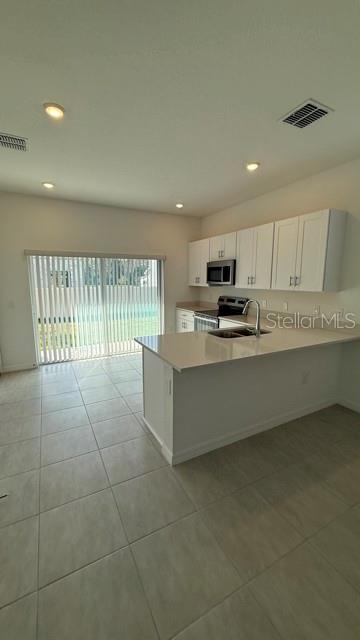 2957 Skyline Loop Kissimmee, FL 34758 - Photo 9 of 23 a large kitchen with kitchen island granite countertop a stove a sink a microwave and a refrigerator