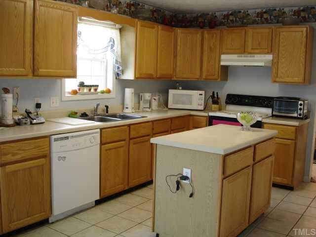 Spacious kitchen with island, ceramic tile floor, and lots of cabinets has updated dishwasher and range.