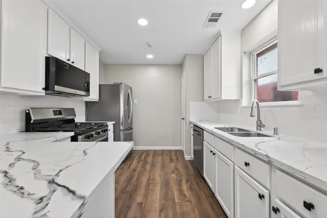 a view of kitchen with kitchen island wooden floor center island and stainless steel appliances