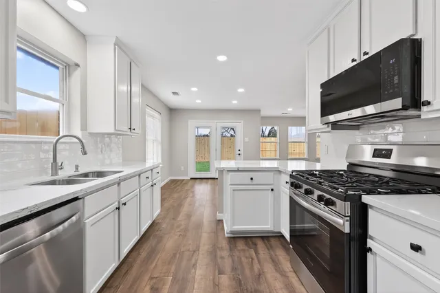 a kitchen with stainless steel appliances a sink a stove and a microwave