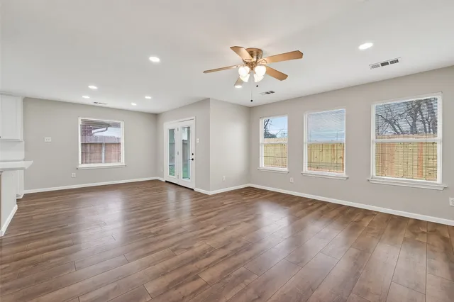 a view of an empty room with window and wooden floor