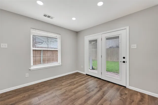 a view of an empty room with a window and wooden floor