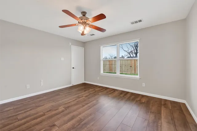 an empty room with wooden floor and chandelier fan