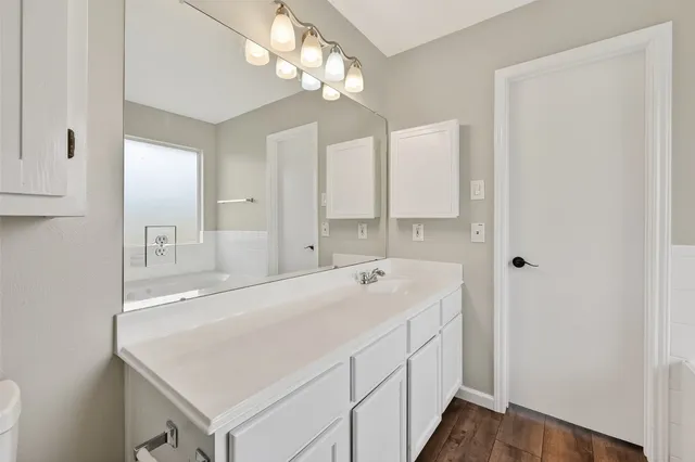 a view of an empty room with wooden floor and a ceiling fan