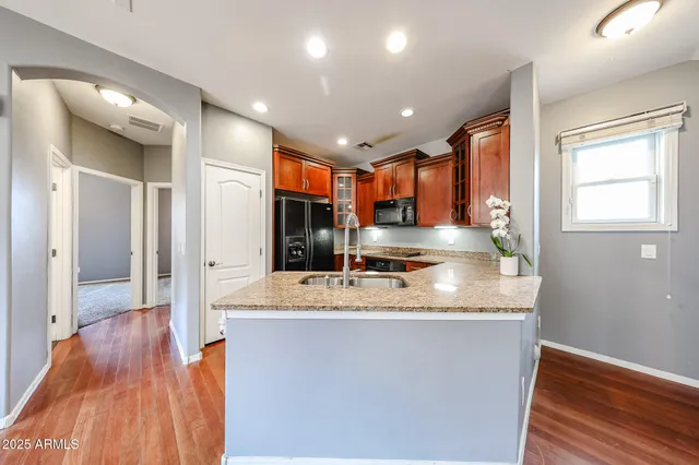 a large kitchen with stainless steel appliances granite countertop a large counter top a sink and a refrigerator