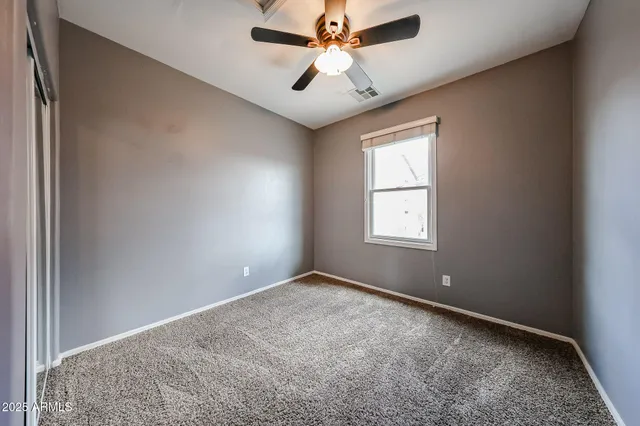 an empty room with windows and fan