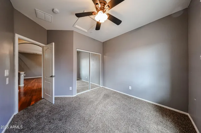 an empty room with closet and a chandelier fan