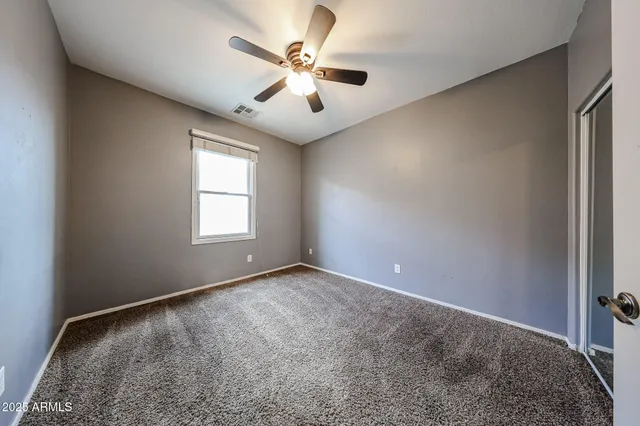 an empty room with windows and ceiling fan