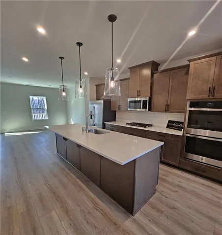 a large kitchen with stainless steel appliances kitchen island granite countertop a stove a sink and a wooden floors