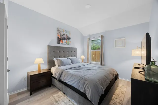 a bedroom with a bed lamp on desk and a window