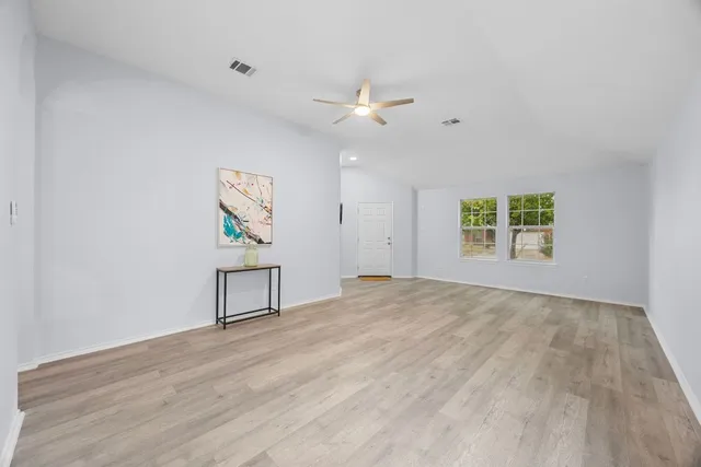 an empty room with windows and ceiling fan