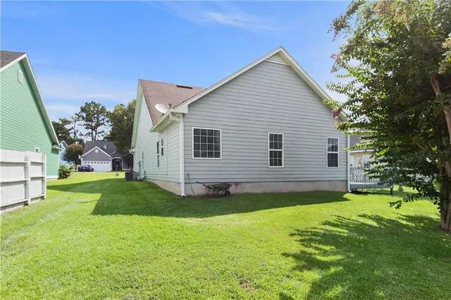 a backyard of a house with plants and large tree