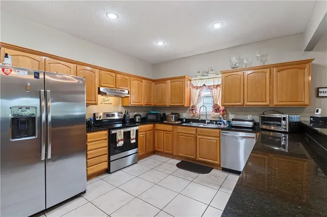 a kitchen with stainless steel appliances granite countertop a refrigerator sink and stove