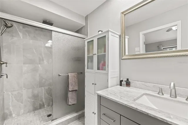 a bathroom with a granite countertop sink a mirror and shower