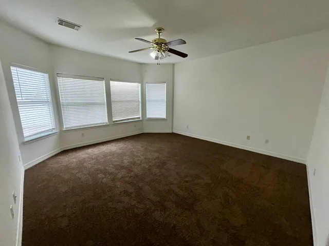 an empty room with windows and fan