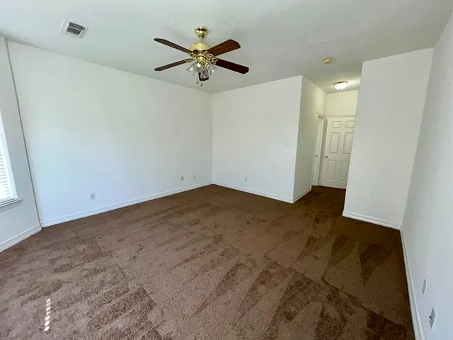 an empty room with a ceiling fan and a window