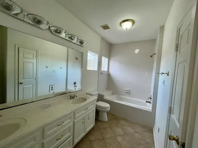 a bathroom with a double vanity sink toilet mirror and bathtub