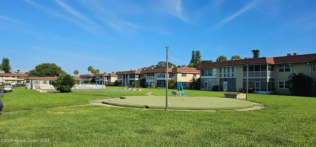 a view of a big house with a big yard and palm trees