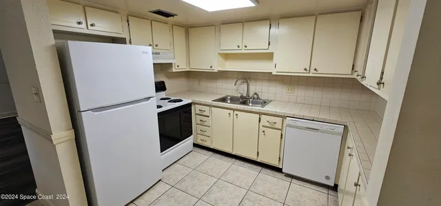 a kitchen with white cabinets sink and refrigerator