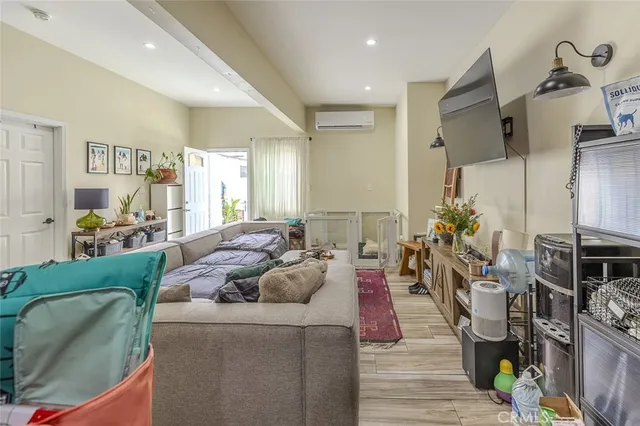 a living room with furniture kitchen view and a wooden floor