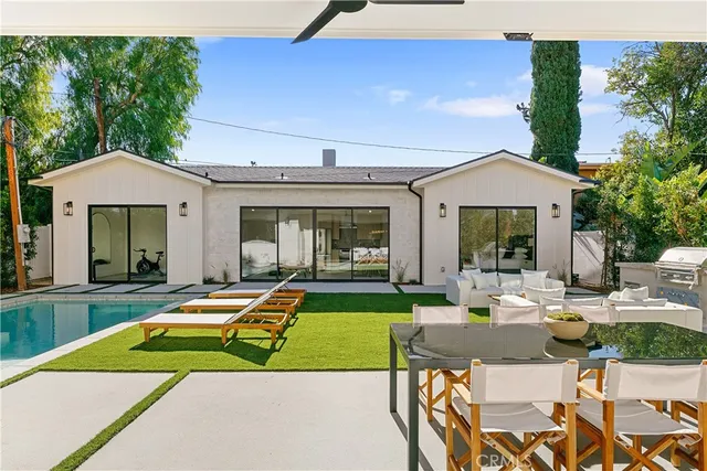a living room with stainless steel appliances furniture a rug and a kitchen view