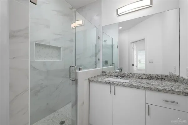 a bathroom with a granite countertop sink a mirror and a shower