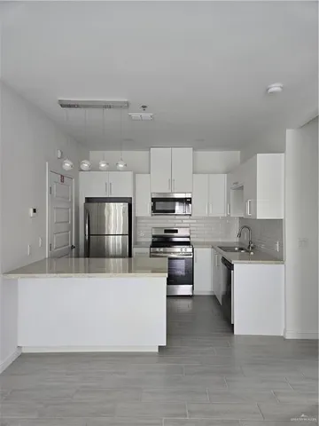 a large kitchen with a large counter top stainless steel appliances and cabinets