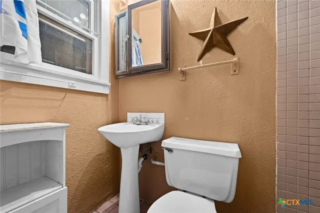 a bathroom with a toilet sink and mirror