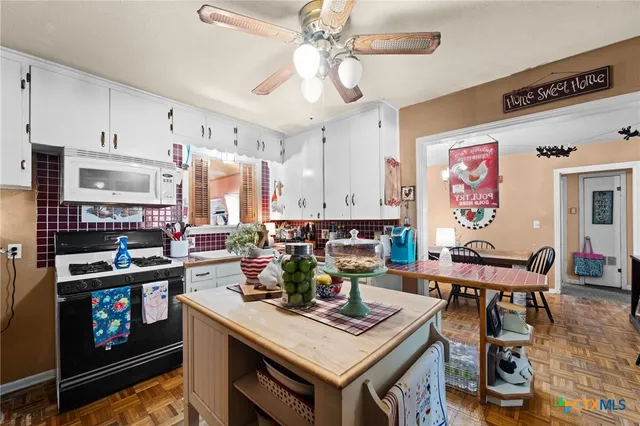 a living room with stainless steel appliances furniture a rug and a kitchen view
