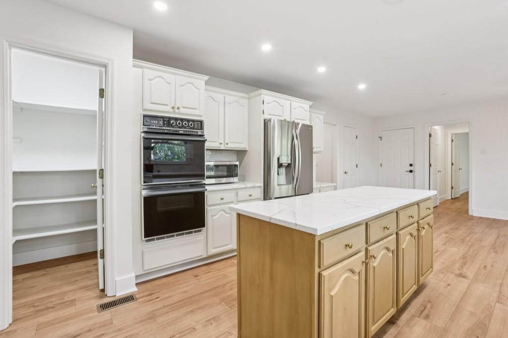 10630 Timberstone Road Alpharetta, GA 30022 - Photo 12 of 42 a kitchen that has a kitchen island wooden cabinets and stainless steel appliances