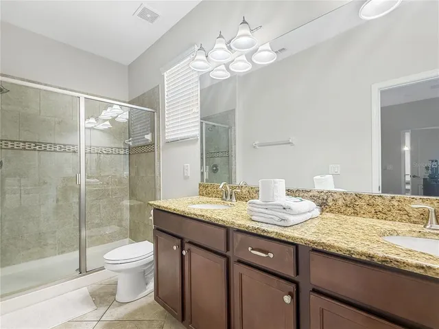 a bathroom with a granite countertop sink a toilet a mirror and shower