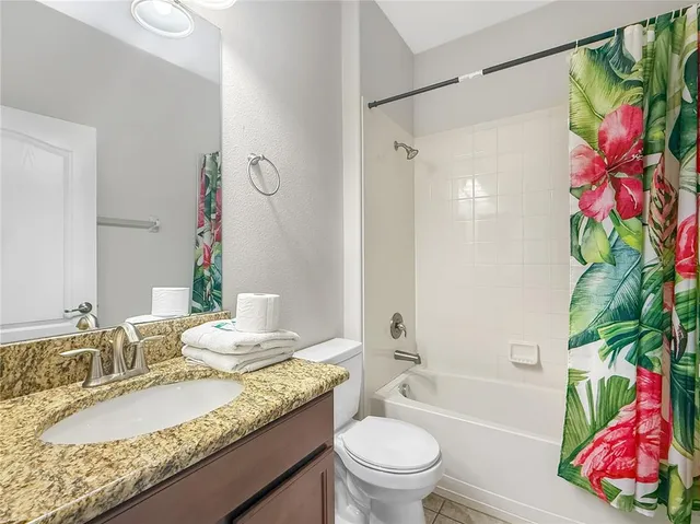 a bathroom with a granite countertop bathtub sink vanity mirror and toilet