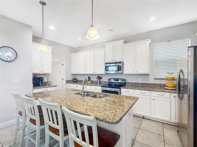 a kitchen with stainless steel appliances granite countertop a stove top oven a refrigerator a sink and a center island