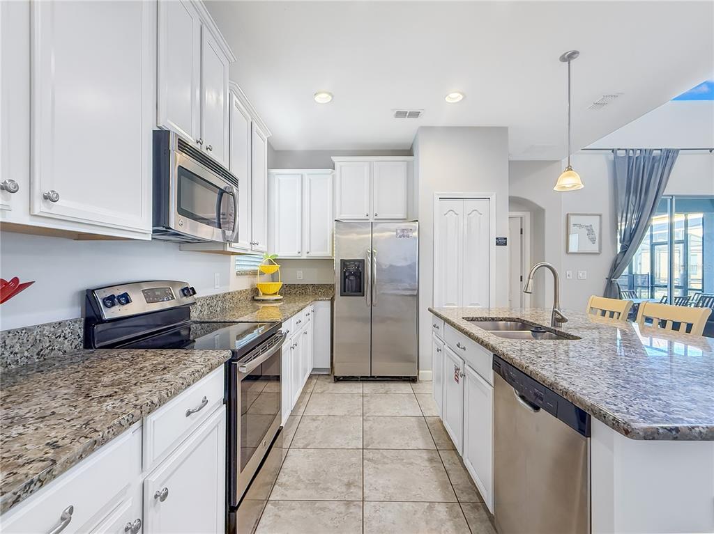 2942 Buccaneer Palm Road Kissimmee, FL 34747 - Photo 9 of 39 a kitchen with stainless steel appliances granite countertop a sink a stove and a refrigerator